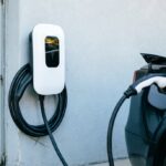 cargador para coche eléctrico doméstico montado junto a la puerta del garaje con un cable enrollado colgando. Enchufado al choche electrico.
