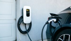 cargador para coche eléctrico doméstico montado junto a la puerta del garaje con un cable enrollado colgando. Enchufado al choche electrico.